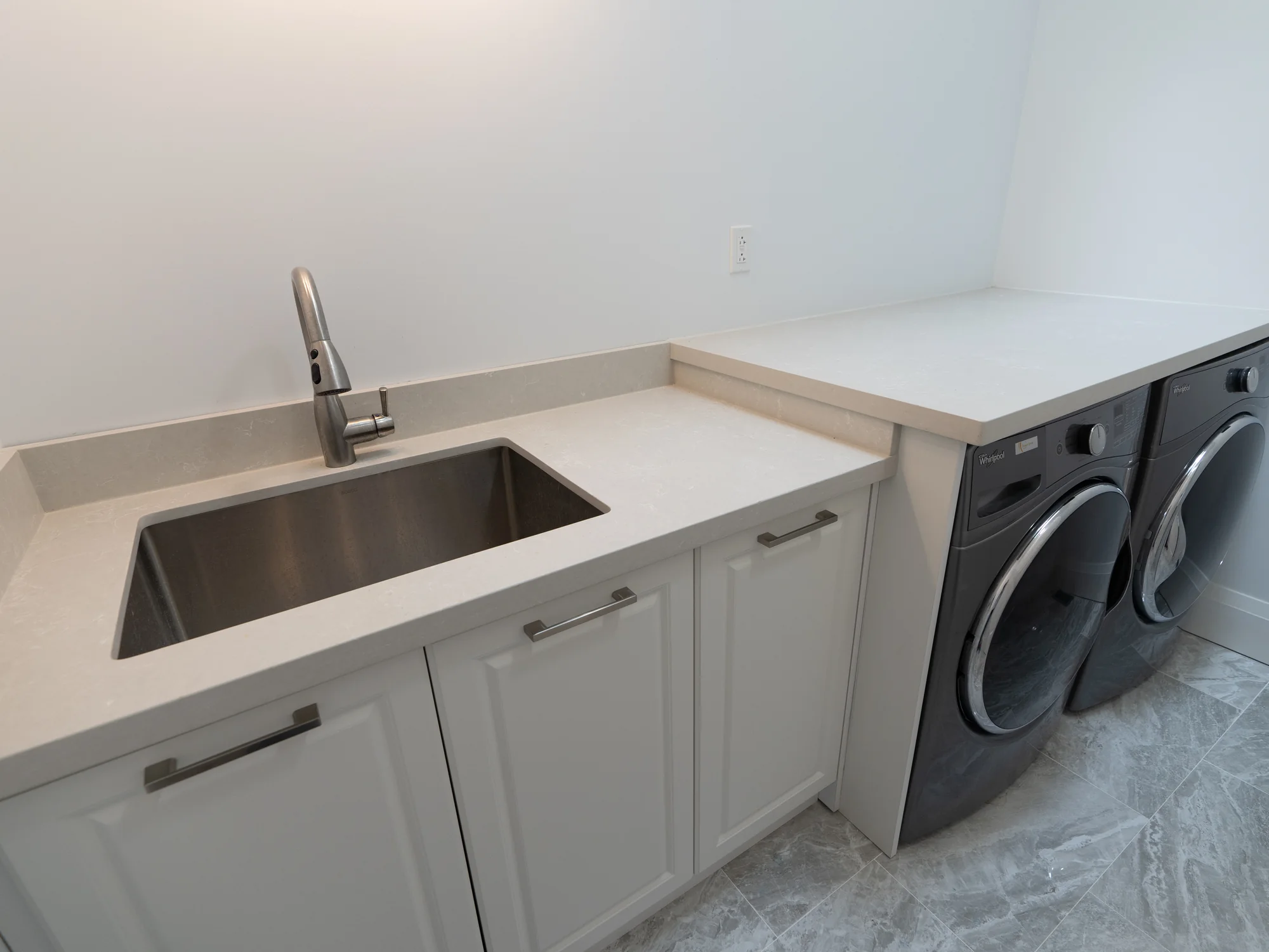 Completed laundry room with a sink, counter, base cabinets, washer, and dryer.