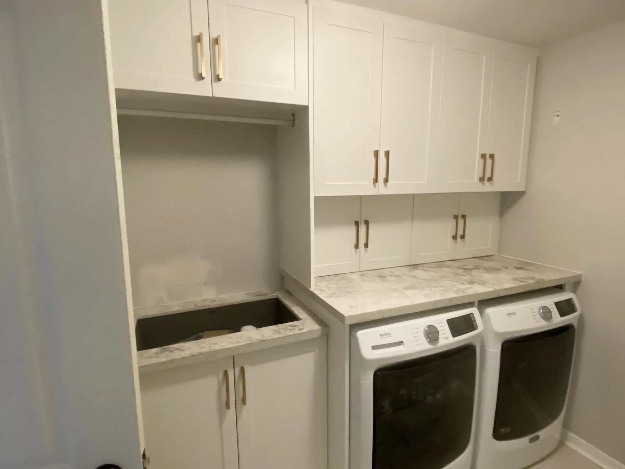 Completed laundry cabinetry fitted above and beside a washer and dryer.