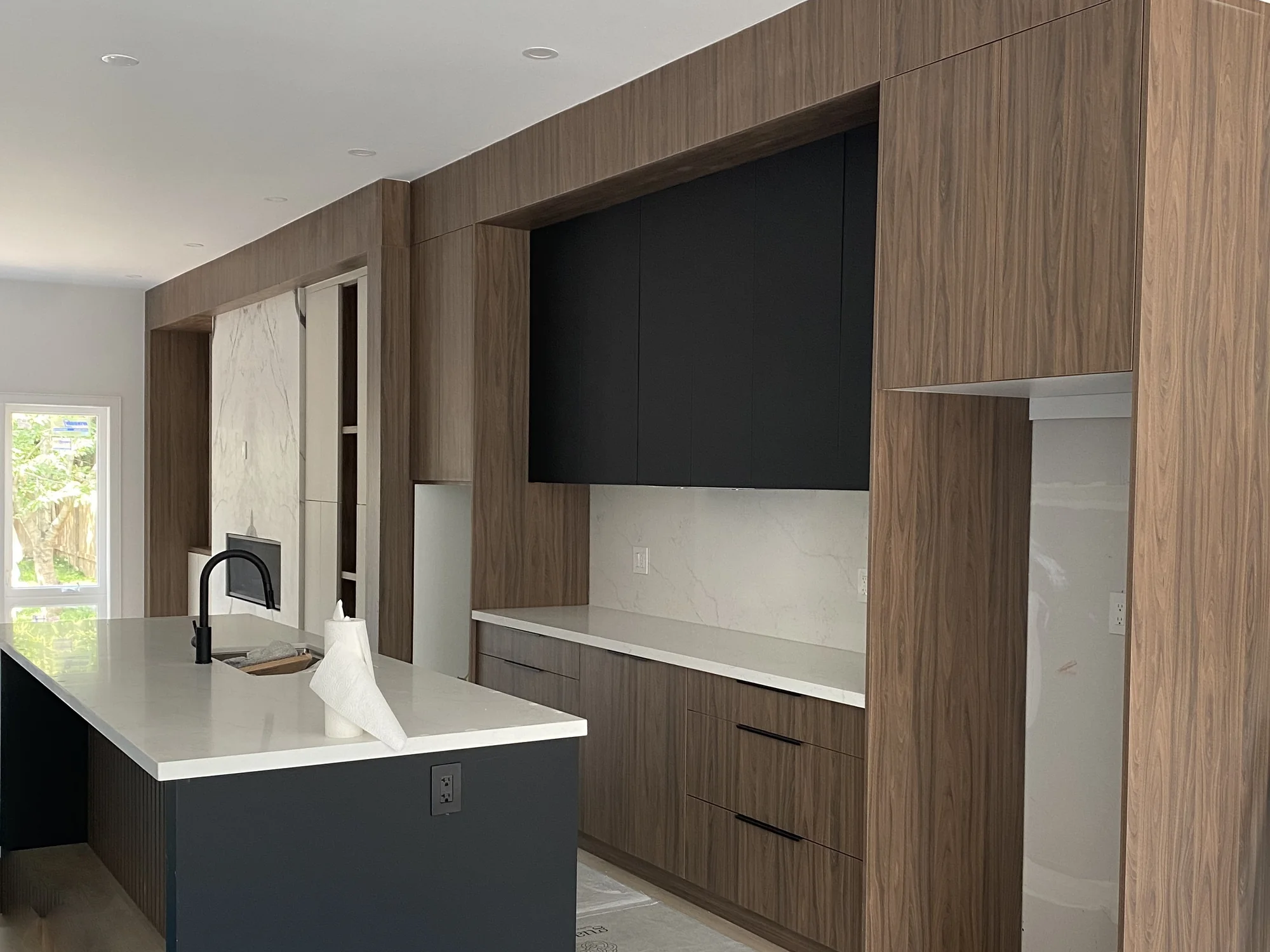 Completed Modern kitchen with wood-grain cabinetry, charcoal flat-panel fronts, and an integrated storage wall.
