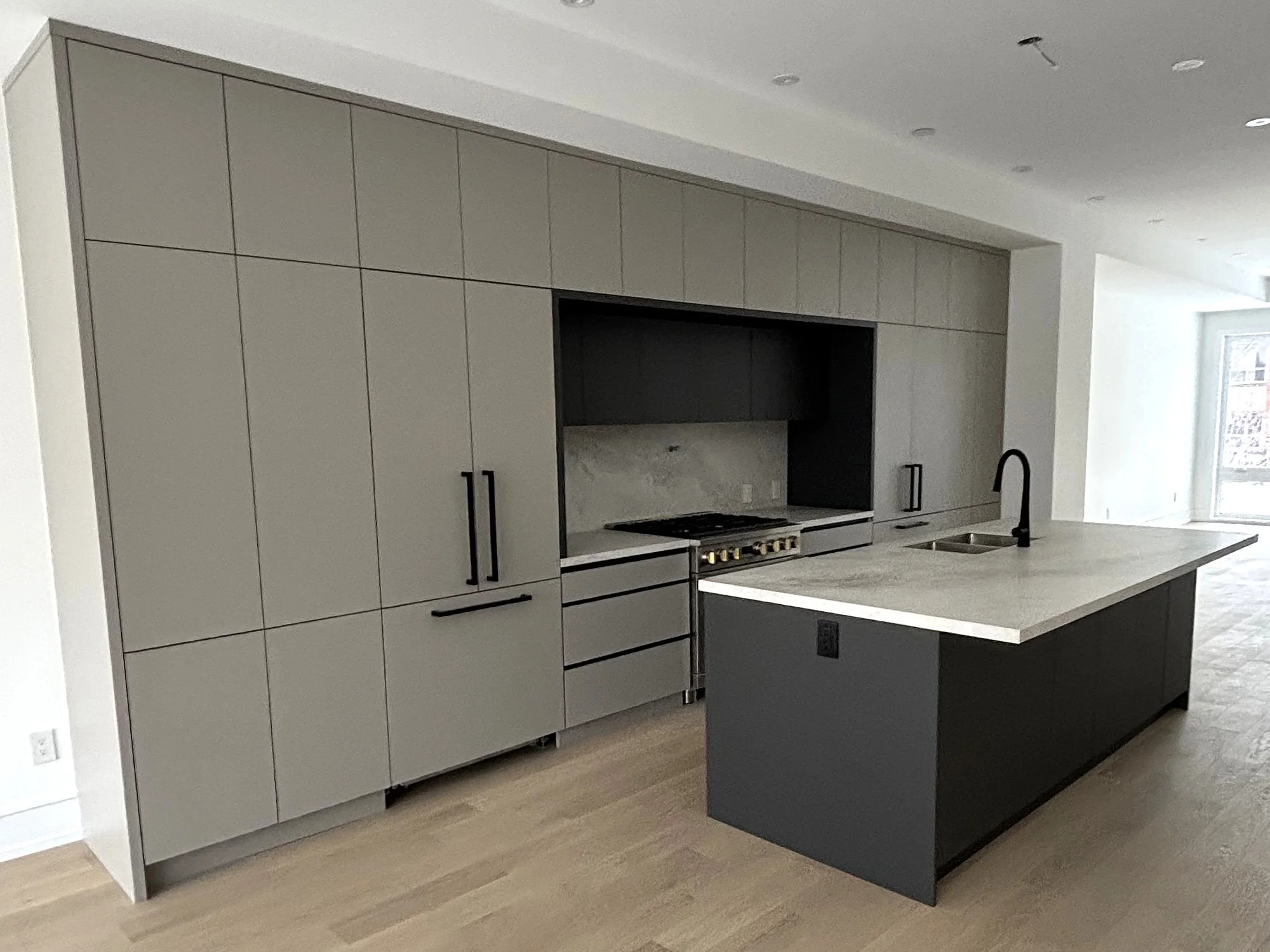 Completed Modern kitchen with matte grey flat-panel cabinetry, a dark island, and clean monolithic surfaces.