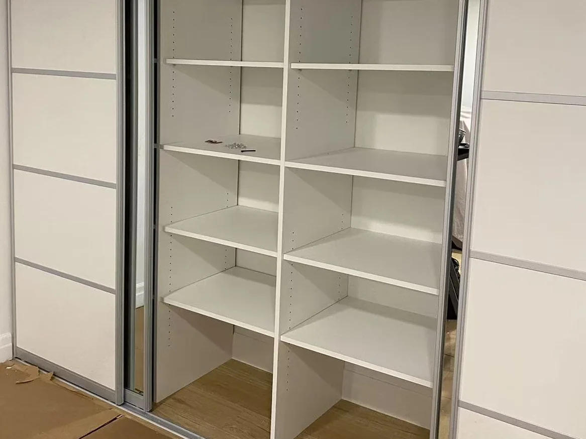 Completed reach-in closet with open shelving and framed sliding panels.
