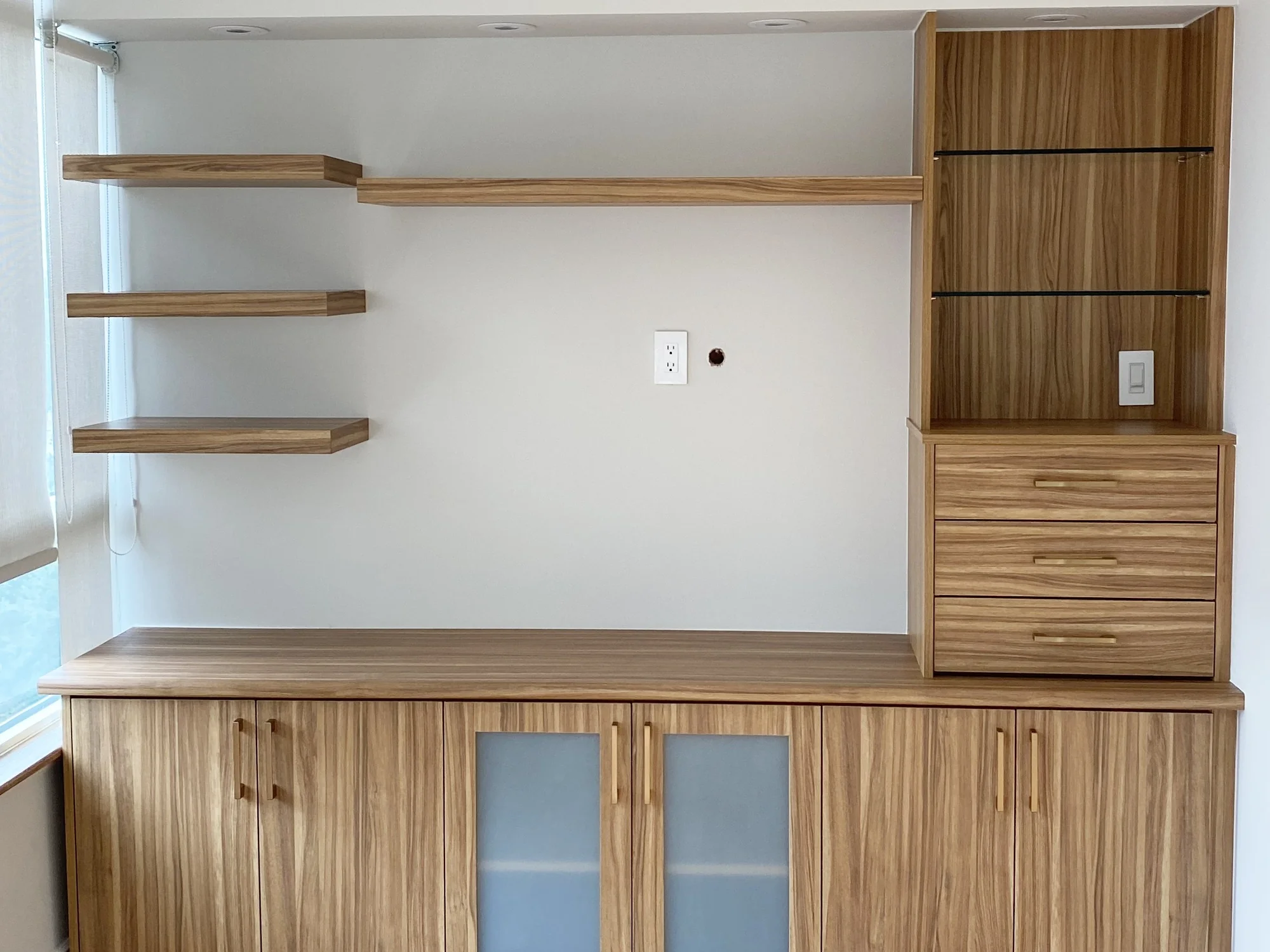 Completed media wall with floating shelves, drawers, and base cabinets.