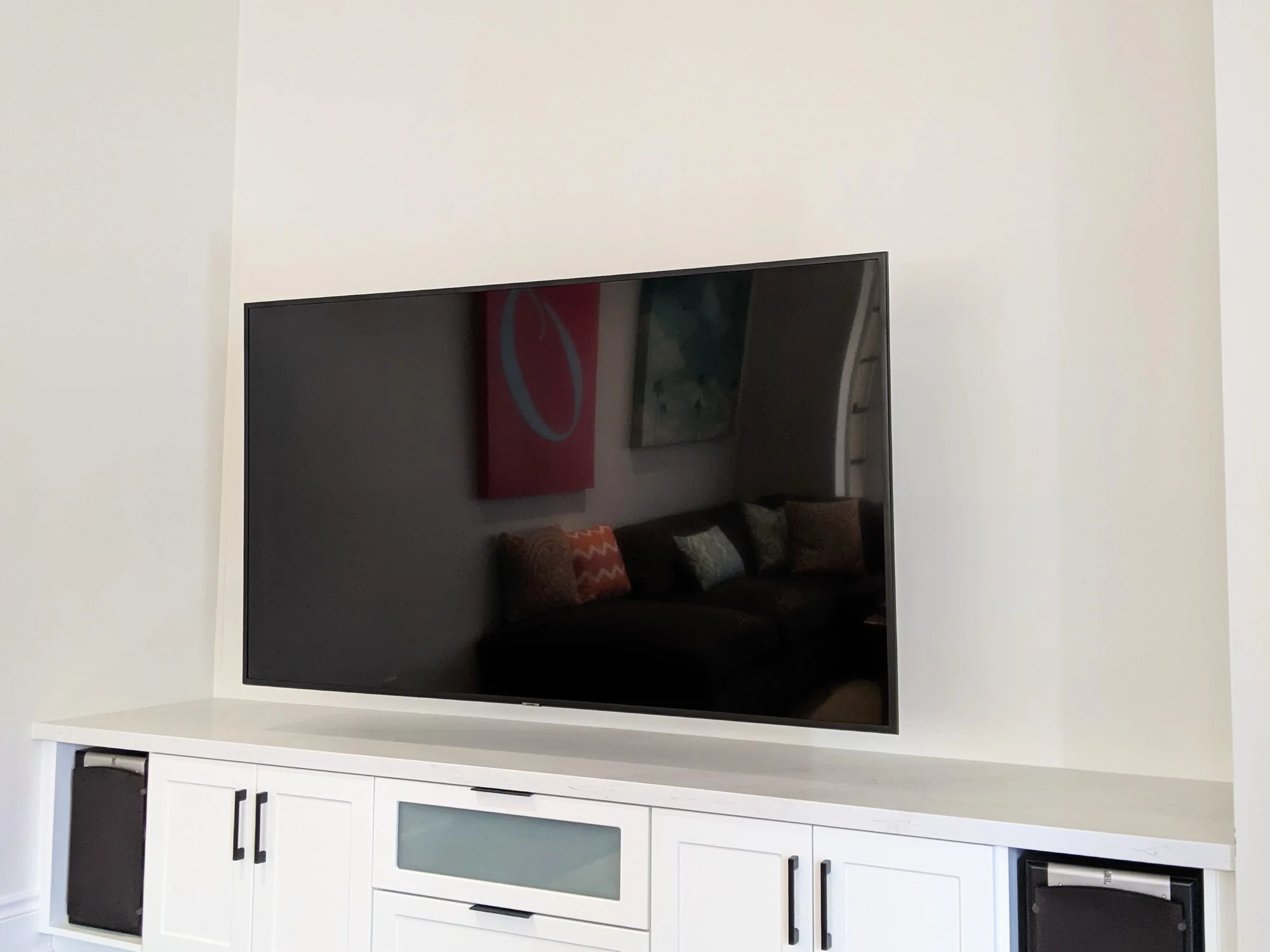 Completed fitted TV base cabinet with drawers, doors, and speaker storage.