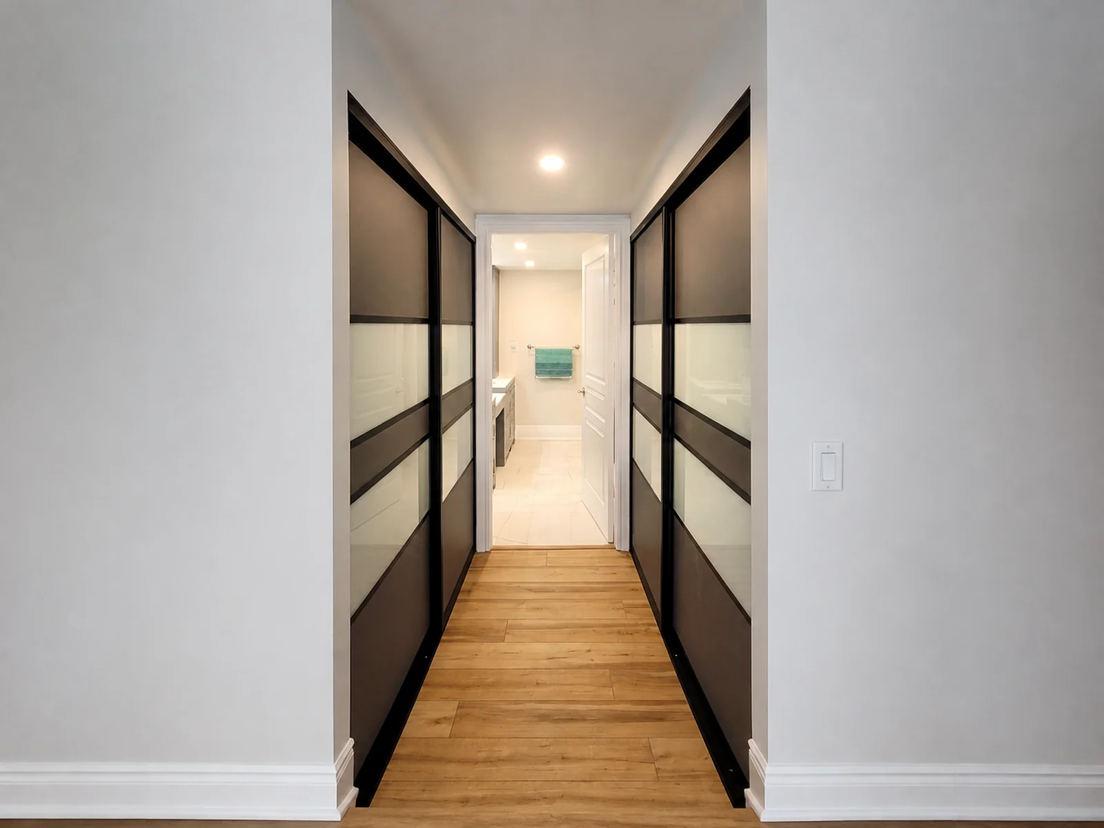 Complete view of sliding closet doors installed along both sides of a bedroom-to-bathroom passage.