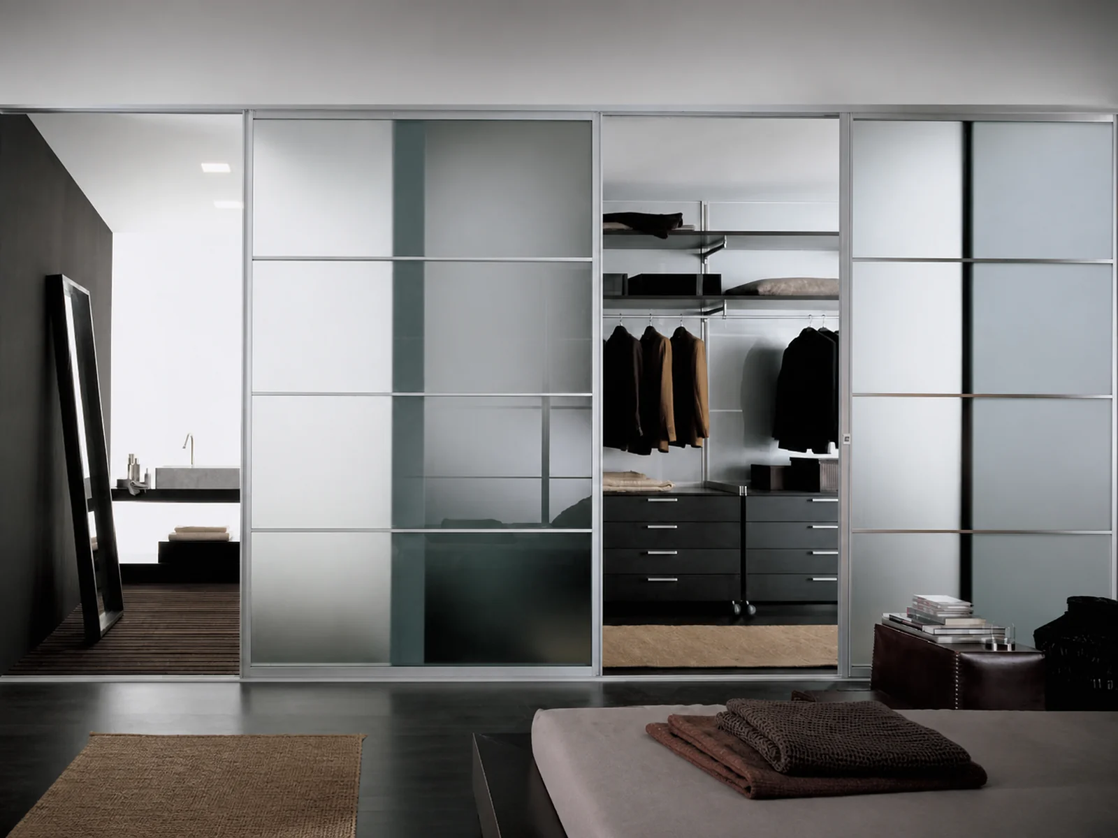 Wide silver-framed sliding door system connecting a bedroom, dressing area, and adjoining space.